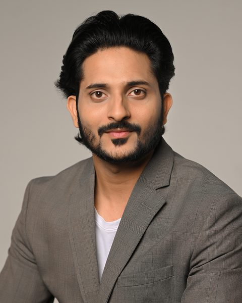 Professional headshot of Neeraj Bansal, Founder and CEO of BeSpoke AI Stylist, wearing a grey plaid blazer over a white shirt